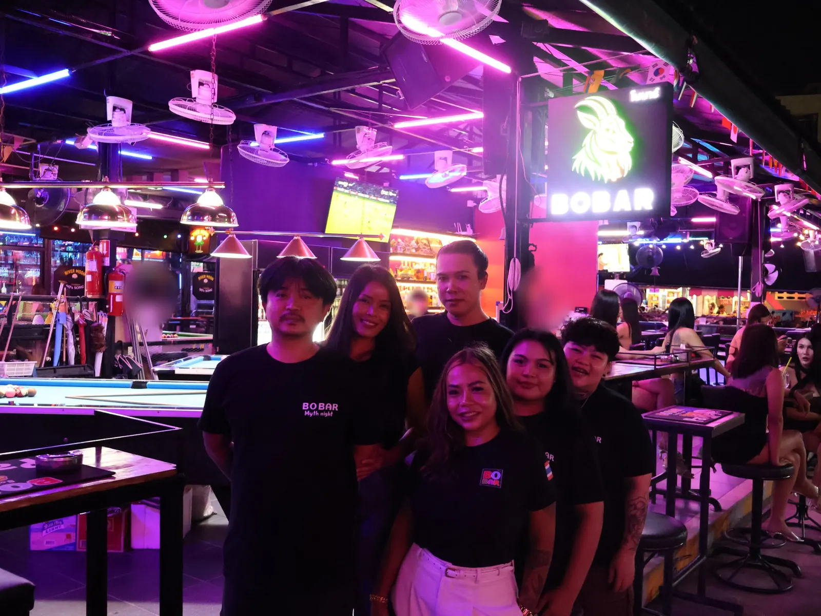The BoBar team standing together in front of the pool tables and the goat sign