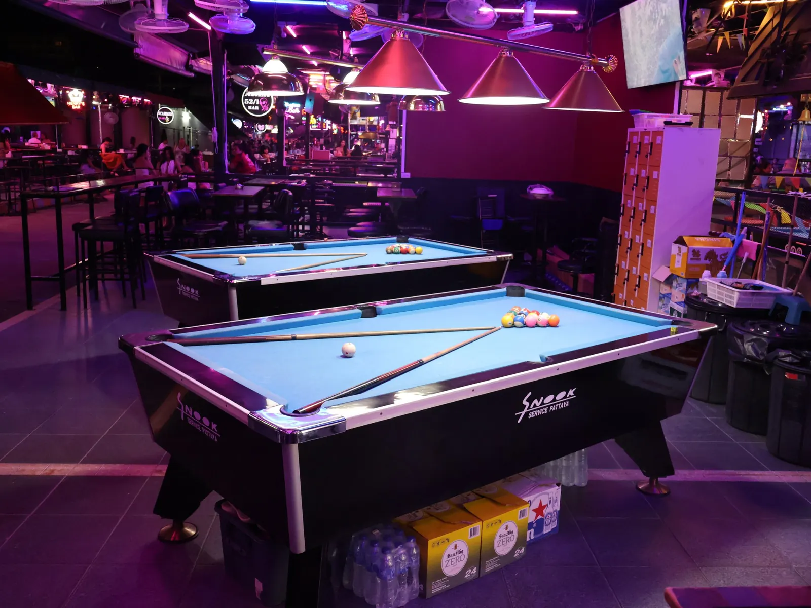 Two blue pool tables ready to play under pendant lamps