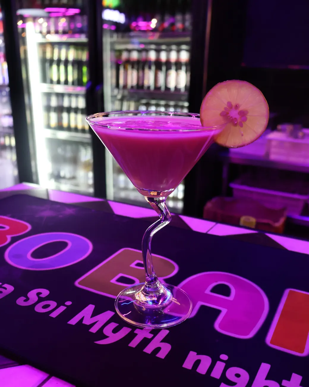A pink cocktail in a martini glass with a slice of lime